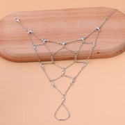 Gold-tone connected hand chain displayed across a wooden surface