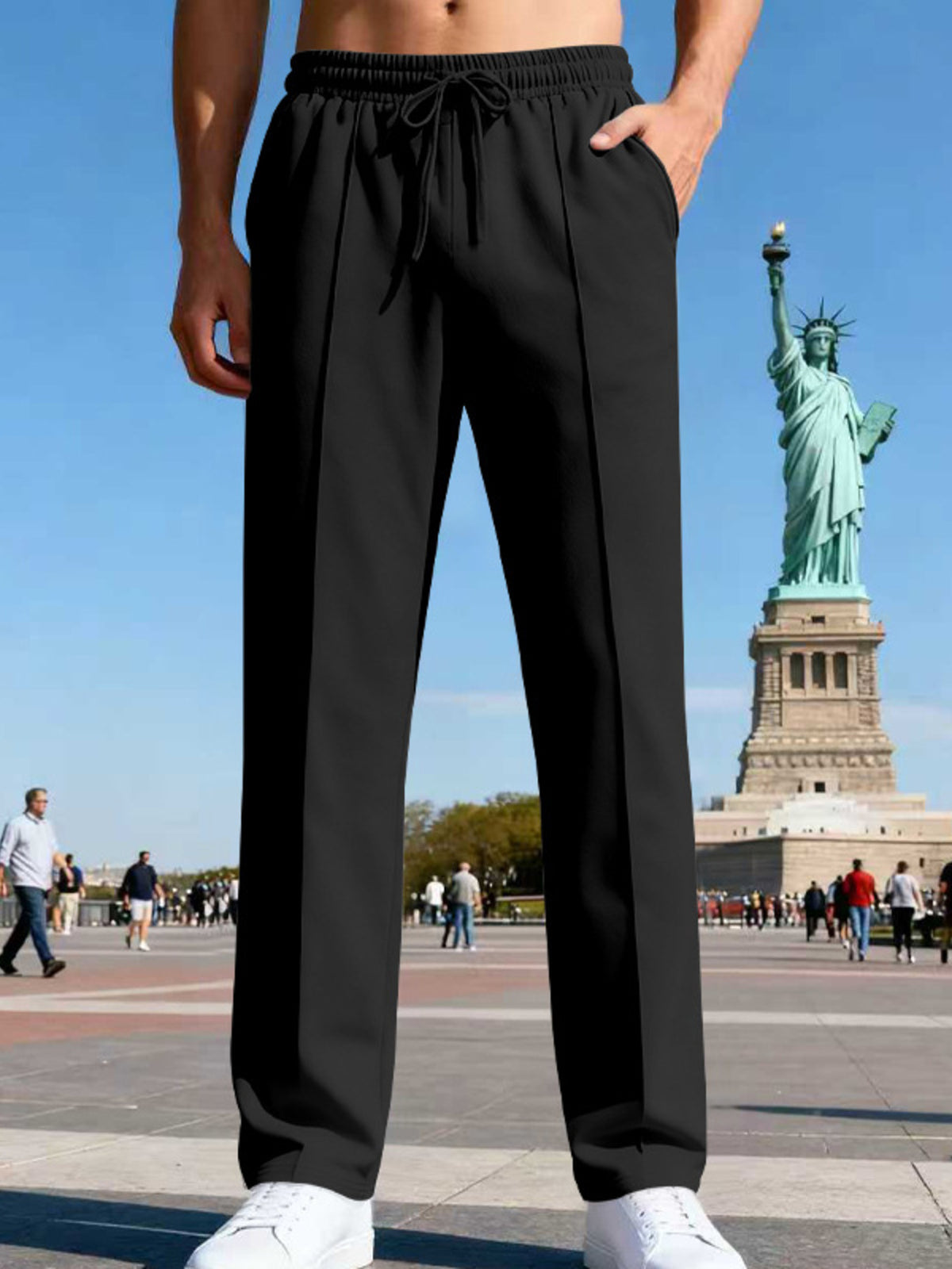 Front view of black straight-leg drawstring pants in a city plaza.