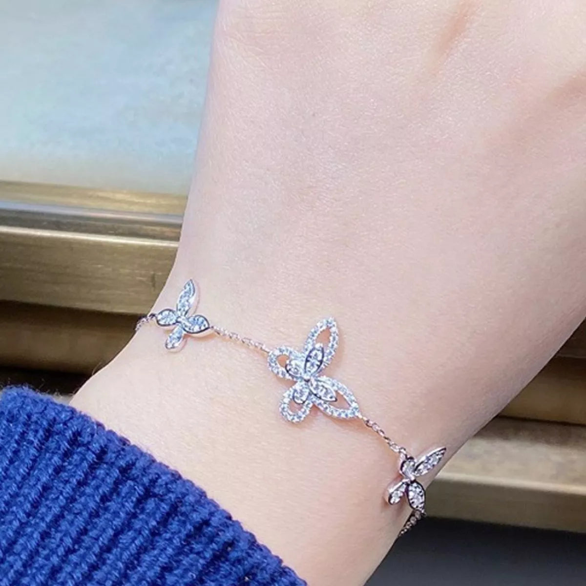 Close view of the butterfly accents on the chain bracelet worn on a wrist