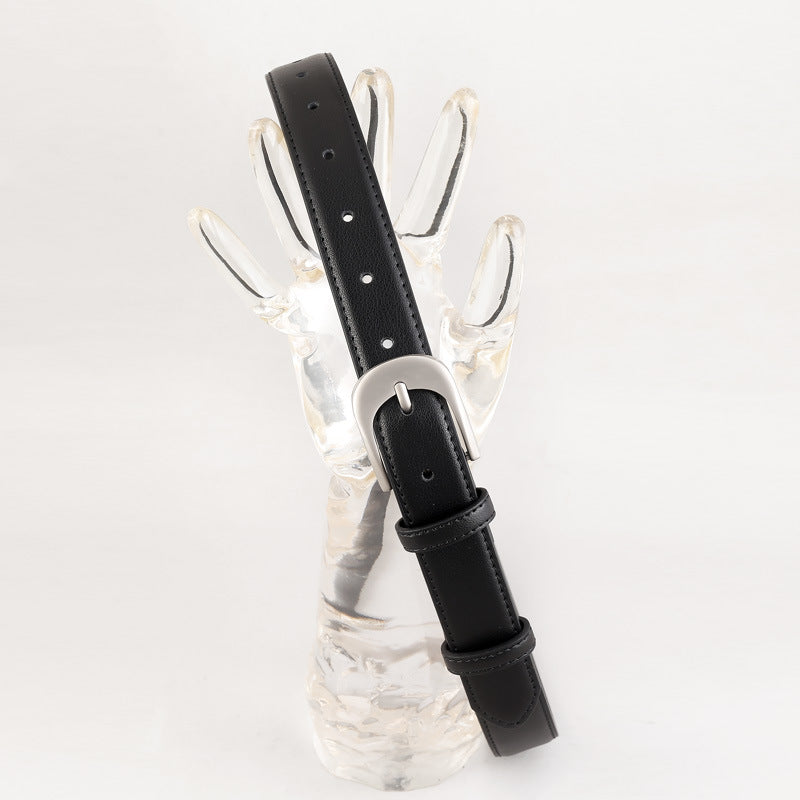 Black stitched belt with silver-coloured buckle draped over a clear hand-shaped display