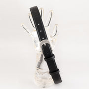 Black stitched belt with silver-coloured buckle draped over a clear hand-shaped display