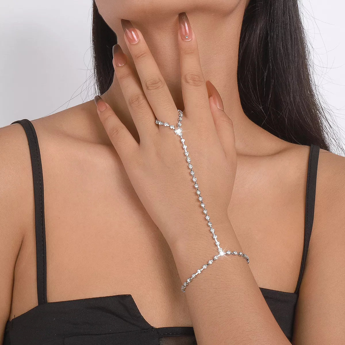 Model wearing rhinestone hand chain bracelet with connected finger ring