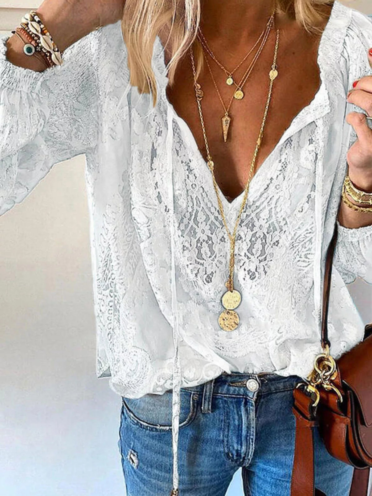 White lace tie-neck blouse shown from front with loose sleeves and denim jeans