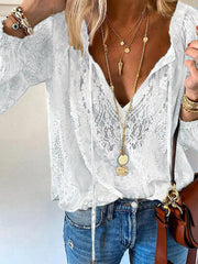 White lace tie-neck blouse shown from front with loose sleeves and denim jeans
