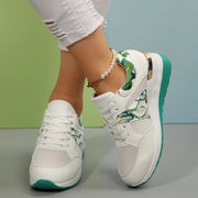 White sneakers with green floral panels and turquoise soles worn at an angle