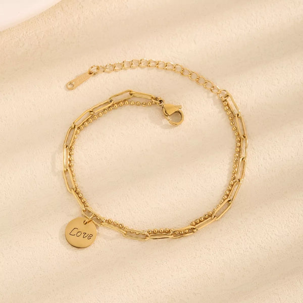 Gold-tone LOVE charm bracelet arranged in a circle with clasp visible