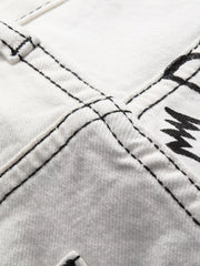 Close-up of double-stitched seam on graffiti-print white jeans