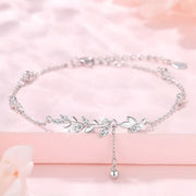 Silver leaf bracelet displayed in a circle on a pink background