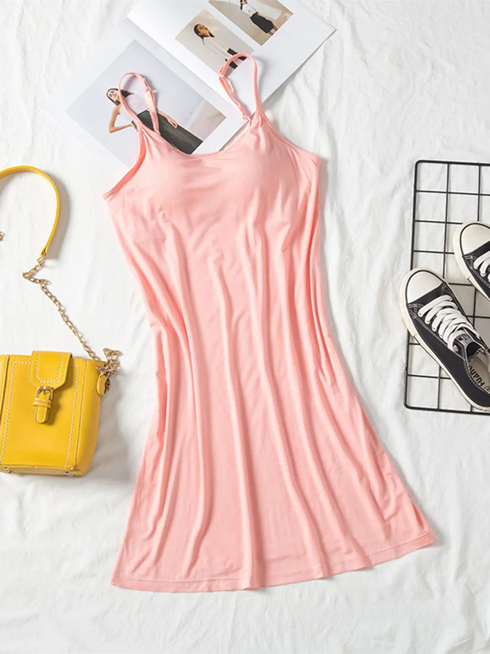 Blush pink spaghetti-strap cami dress laid flat with round neckline and fitted waist