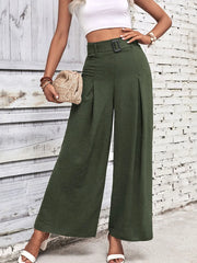 Model carrying a clutch while wearing olive green wide-leg trousers.
