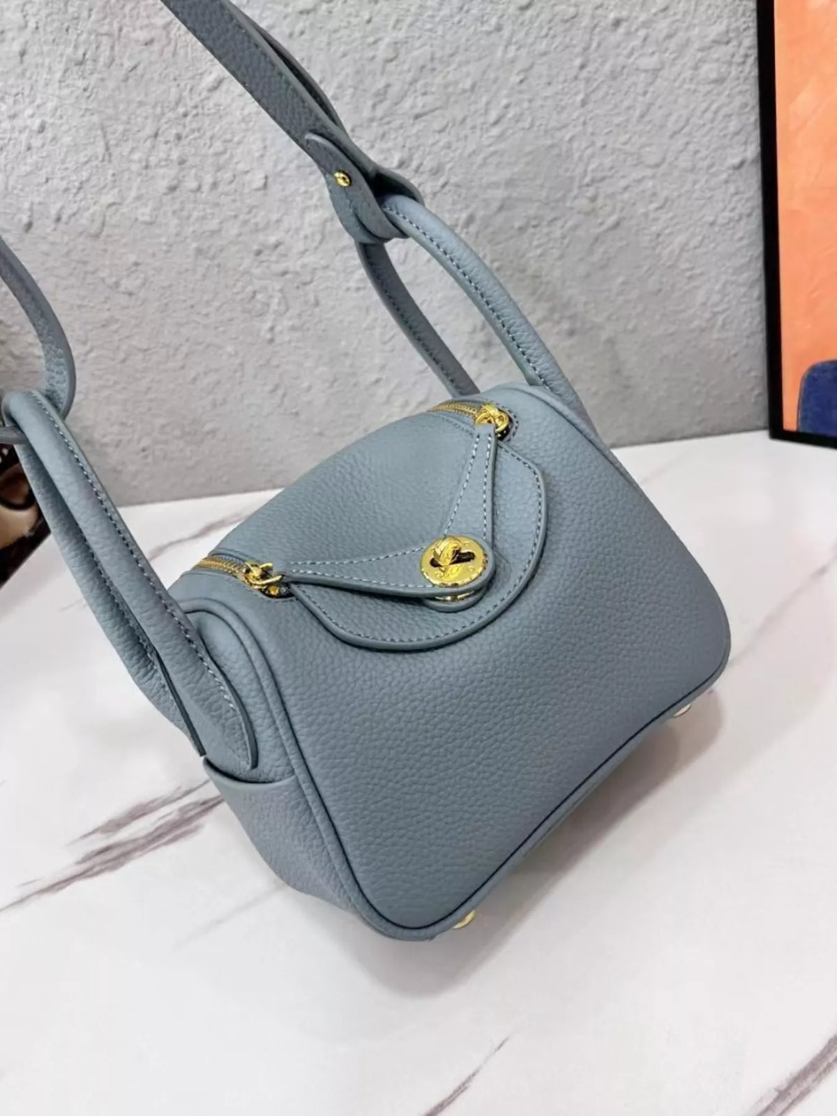 Angled view of a blue crossbody bag with flap closure