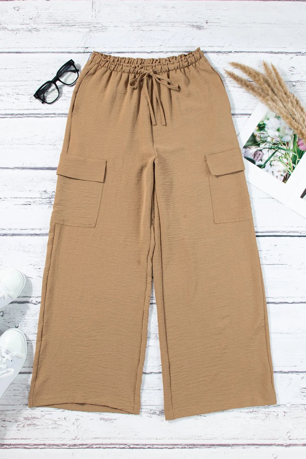 Tan utility trousers laid flat to show the front and cargo pockets