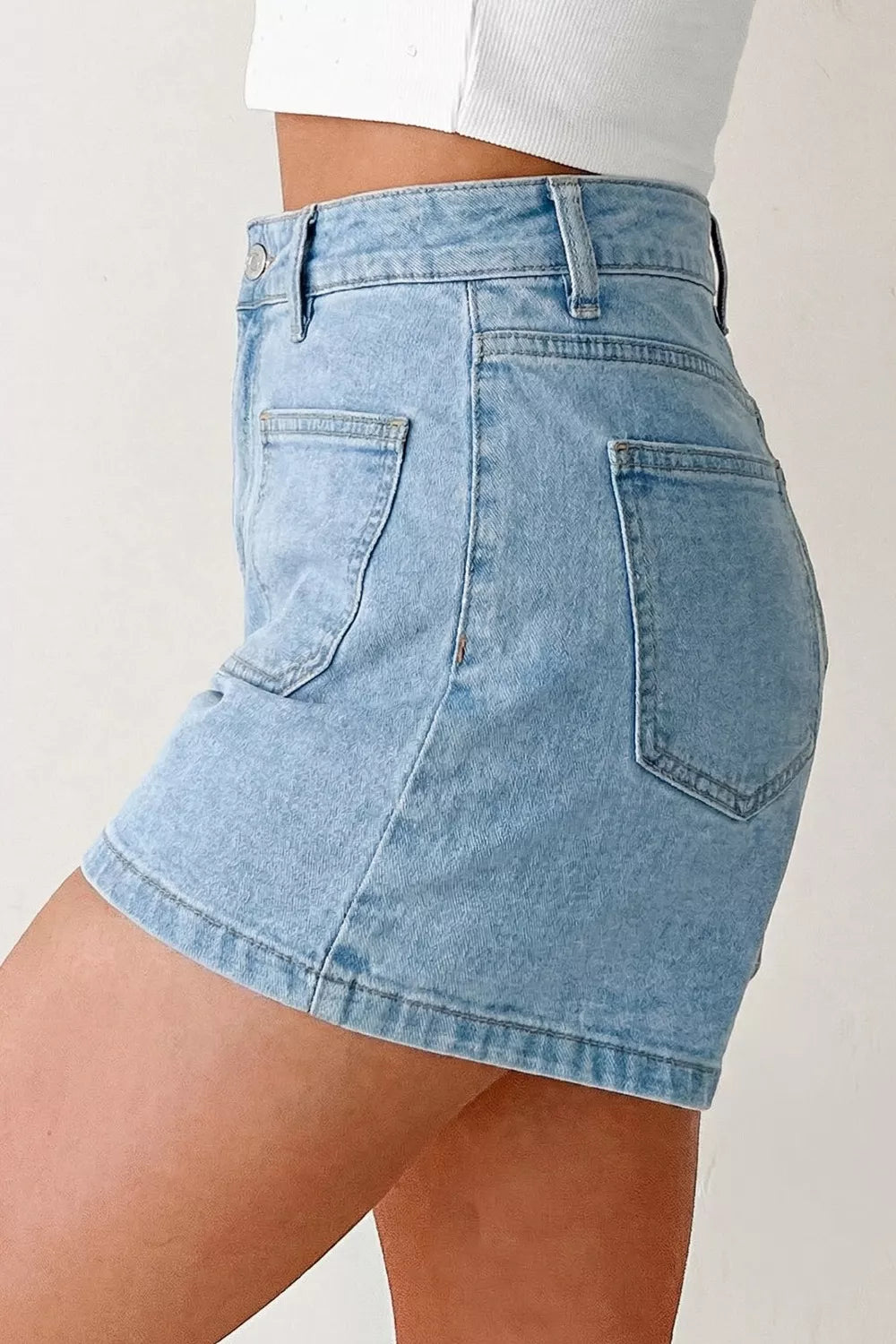 Side view showing patch pocket on light-blue denim shorts