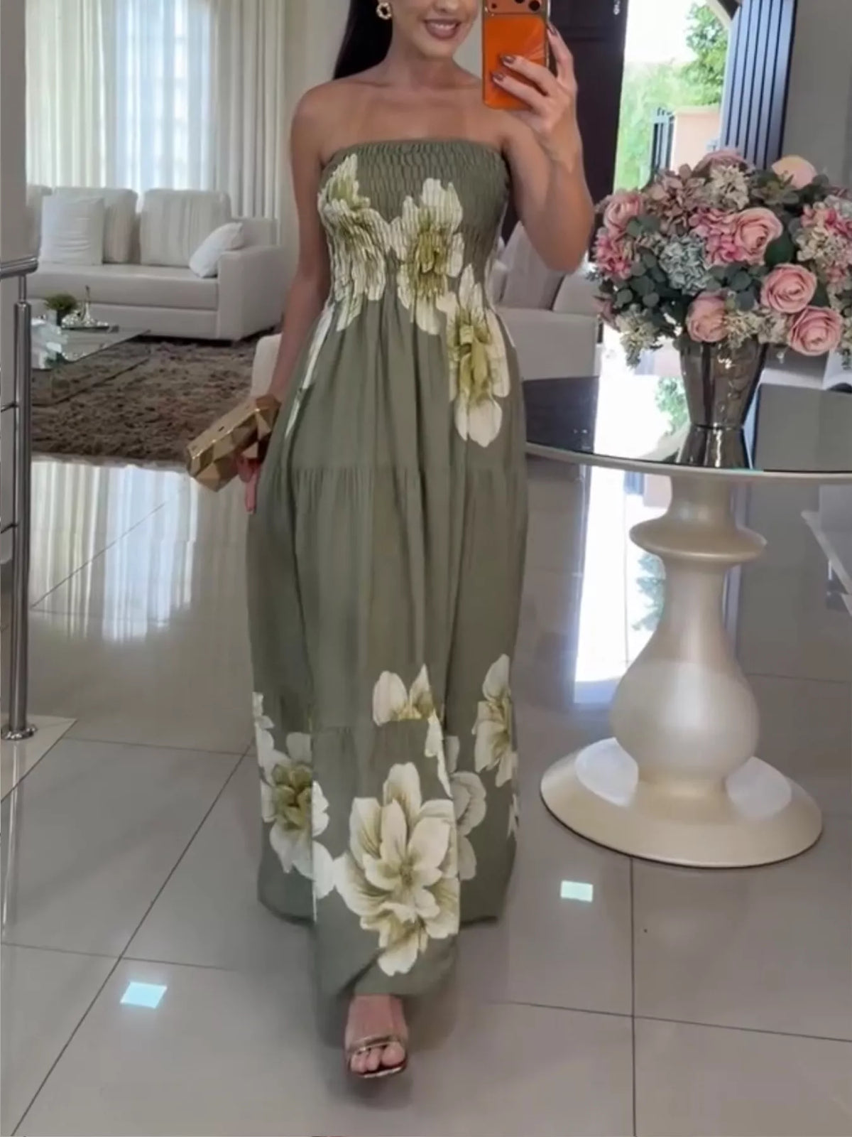 Model wearing a green floral strapless maxi dress with a tiered skirt, viewed at full length.