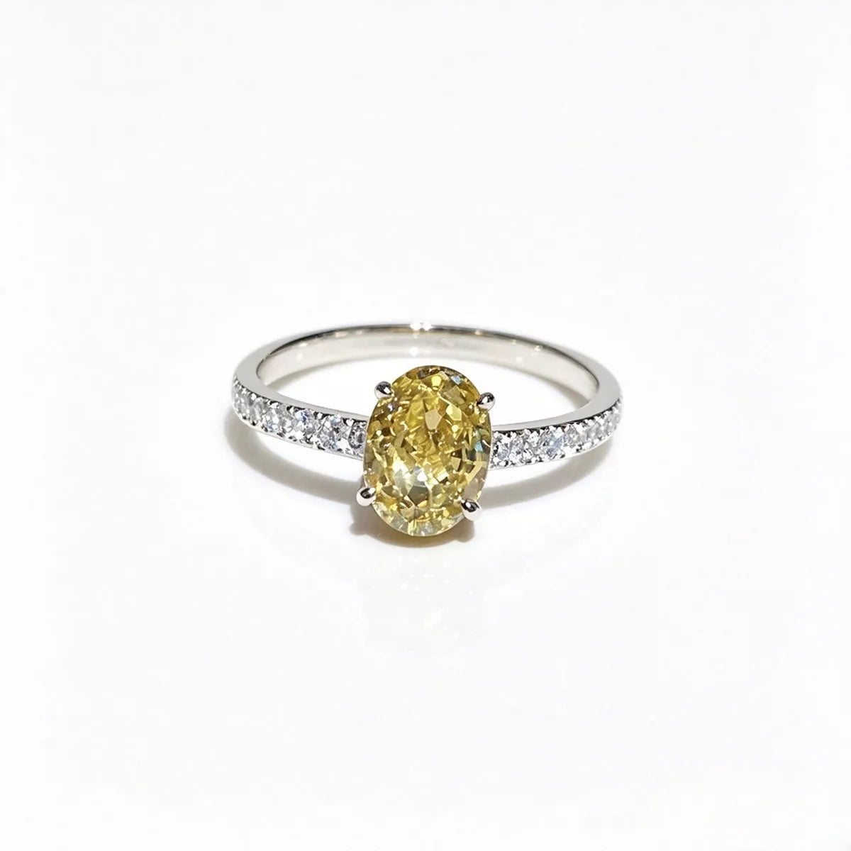 Oval yellow center stone on a polished copper-tone ring with clear stones along the shoulders