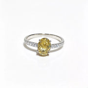 Oval yellow center stone on a polished copper-tone ring with clear stones along the shoulders