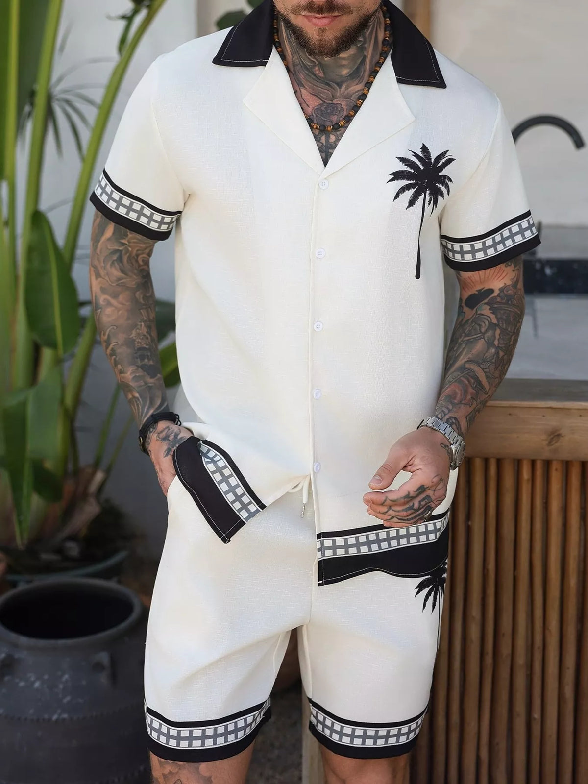 Model wearing white palm-tree print shirt and matching shorts