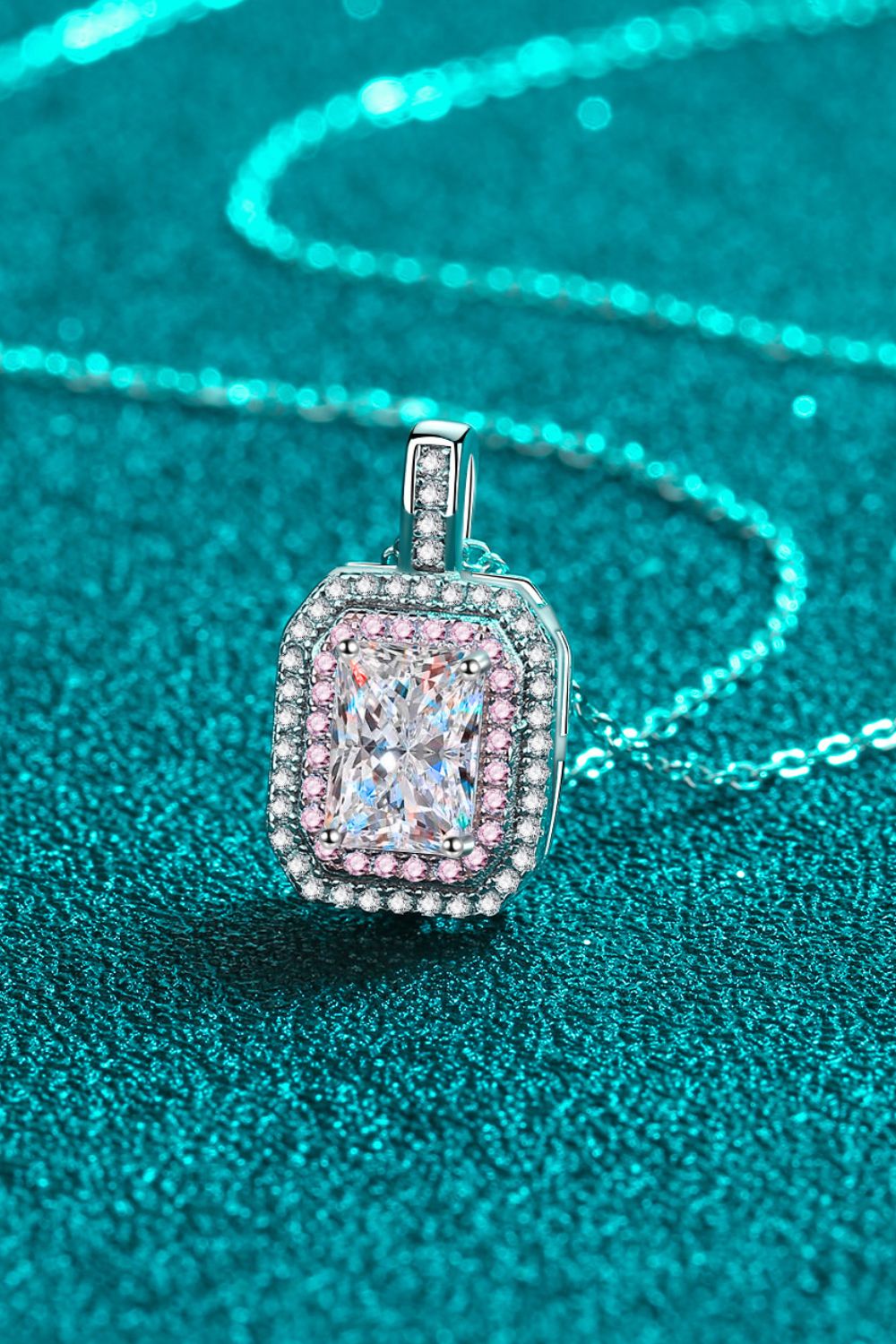 Angled close-up of a pink-bordered rectangular pendant and silver-tone chain