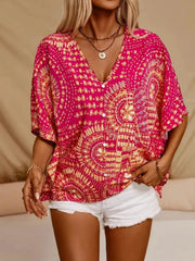 Pink printed blouse on a model with hands at the pockets of white denim shorts.