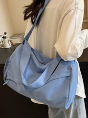 Blue duffel bag worn on the shoulder with the side compartment visible