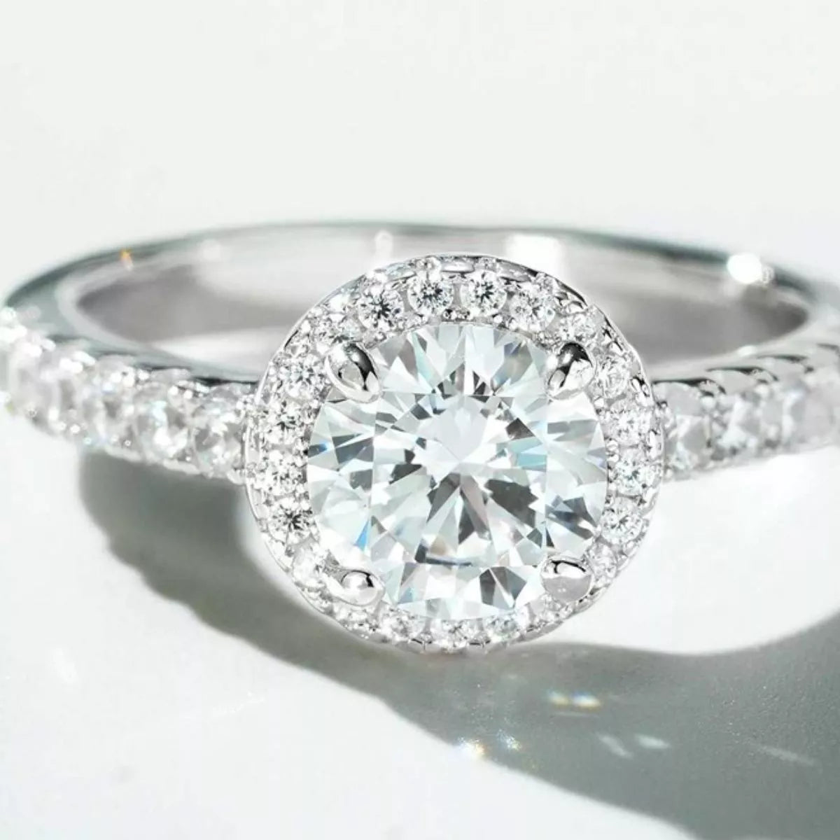 Close-up of the round clear center stone, halo and detailed ring shoulders