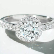 Close-up of the round clear center stone, halo and detailed ring shoulders