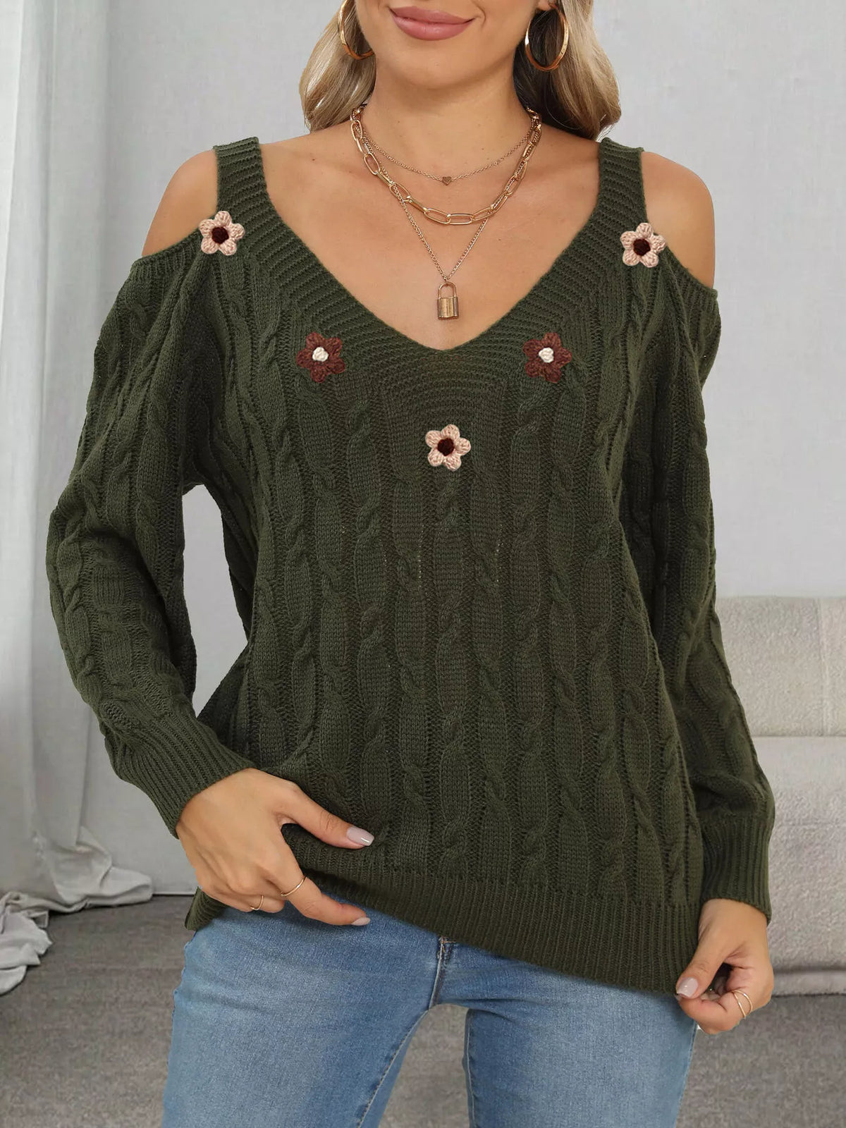 Front view of dark olive cable-knit sweater with embroidered flower appliqués