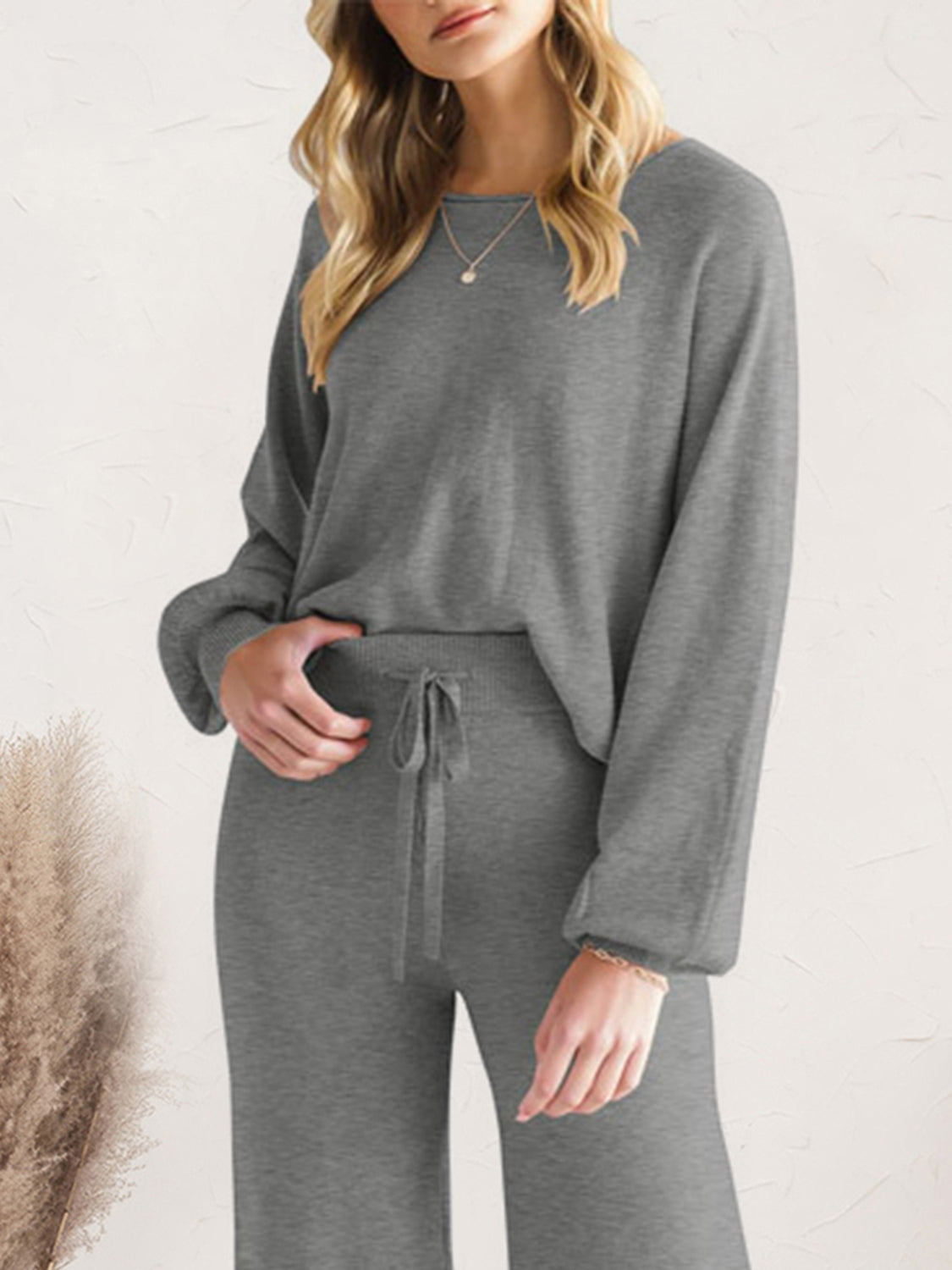 Close view of charcoal lounge top and drawstring pants with one hand in pocket