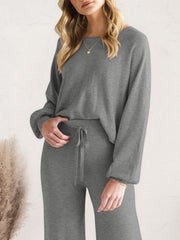 Close view of charcoal lounge top and drawstring pants with one hand in pocket