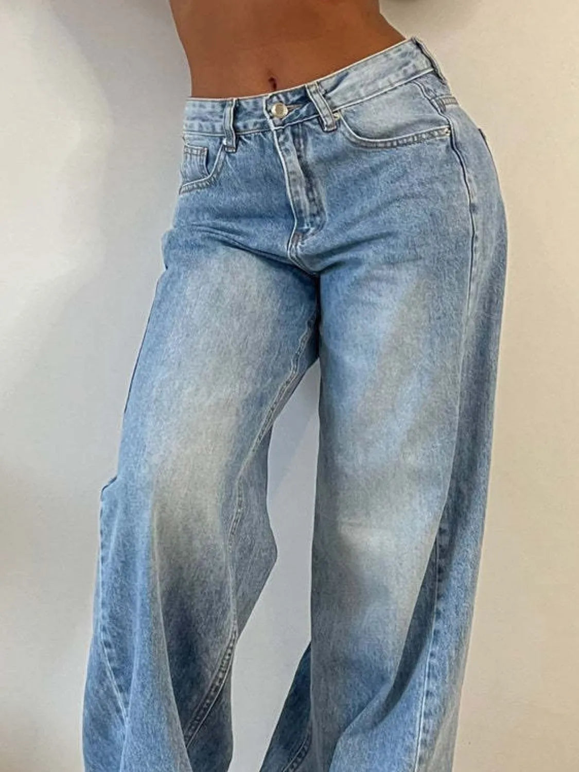 Close view of light blue wide-leg jeans showing the front pockets and button closure