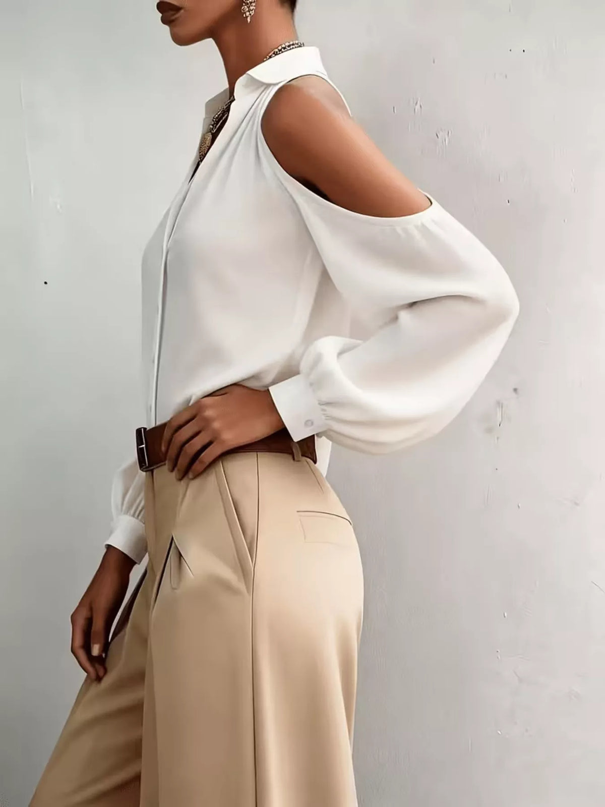 Side view of white blouse with shoulder cutout and flowing sleeve.