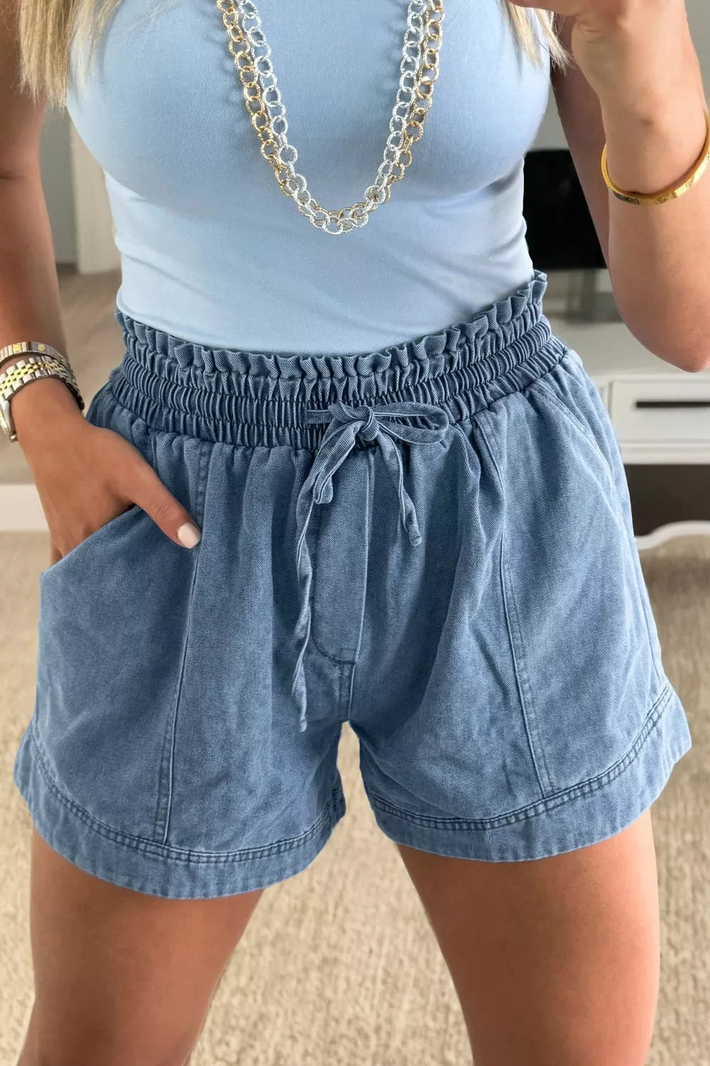 Front view of blue denim shorts with a gathered elastic waist and drawstring