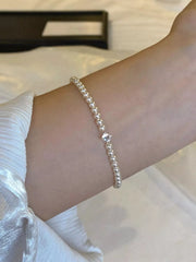 Close view of the adjustable pearl bracelet worn on a wrist.