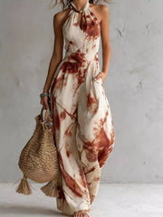 Cream jumpsuit with rust-red ink-wash print, full-length front view with a woven bag.