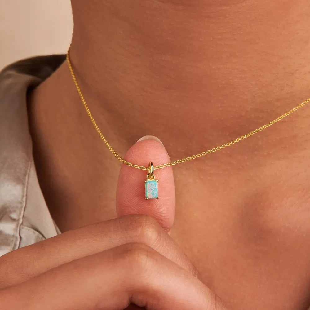 Model holding a pale aqua rectangular pendant on a gold-tone chain