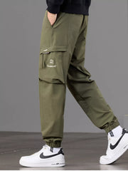 Side view of olive joggers highlighting the large flap pocket and cuffed ankle.