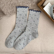 Pair of gray socks with small dark motifs and navy scalloped cuffs laid flat