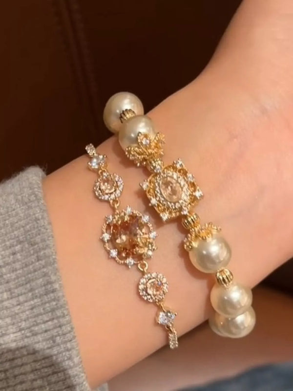 Gold-tone bracelet with pearl beads and floral crystal links worn on a wrist