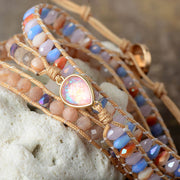 Close-up of pastel faceted beads and pink iridescent teardrop stone on a woven wrap bracelet