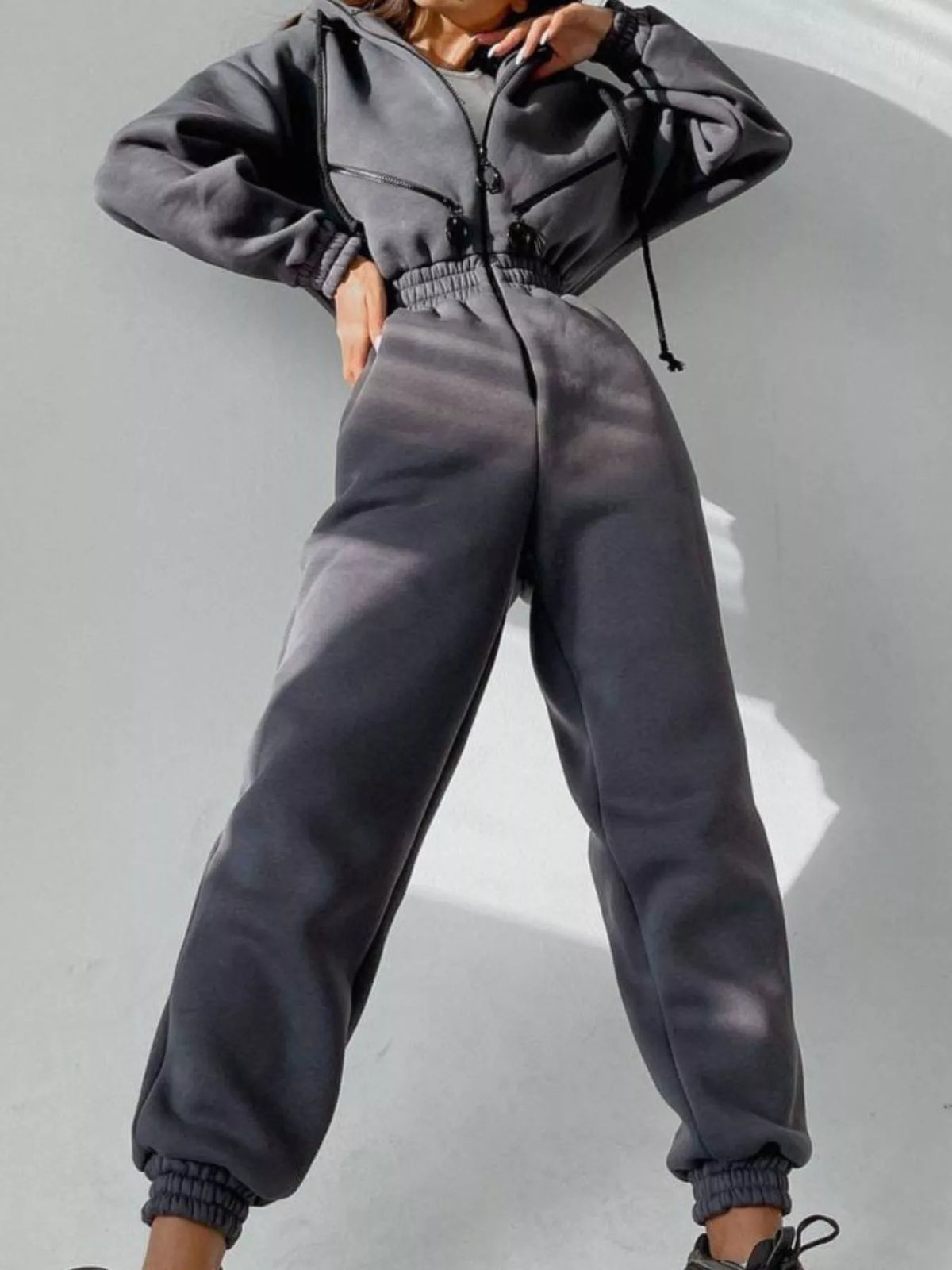 Women's charcoal hooded jumpsuit, model front pose with hands at waist