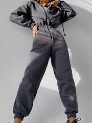 Women's charcoal hooded jumpsuit, model front pose with hands at waist