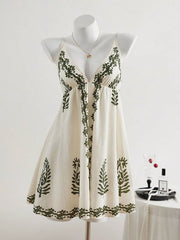 Ivory sleeveless V-neck mini dress with dark botanical embroidery displayed on a mannequin