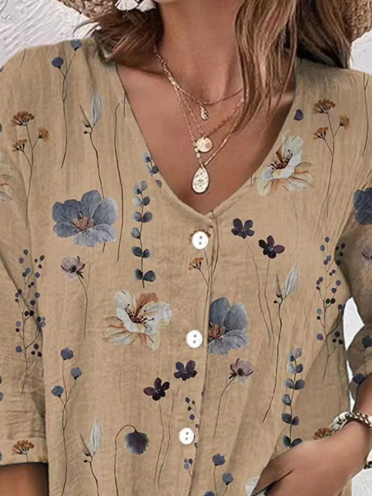 Close-up of beige blouse with blue floral print and button placket.