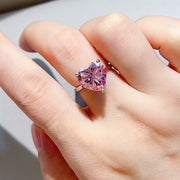 Pink heart-shaped moissanite ring worn on a hand.