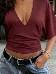 Burgundy T-shirt detail showing the gathered waist and cropped hem above jeans.