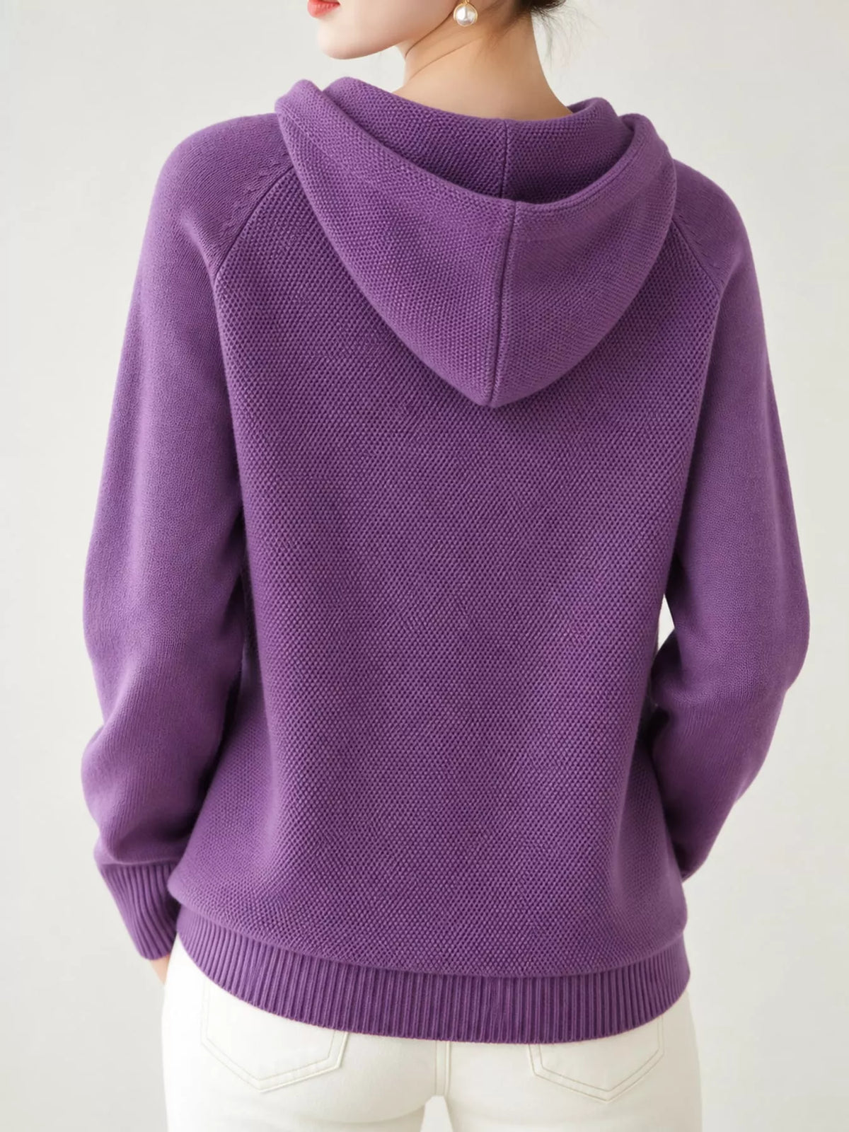 Back view of the purple knit sweater showing its hood and ribbed hem.