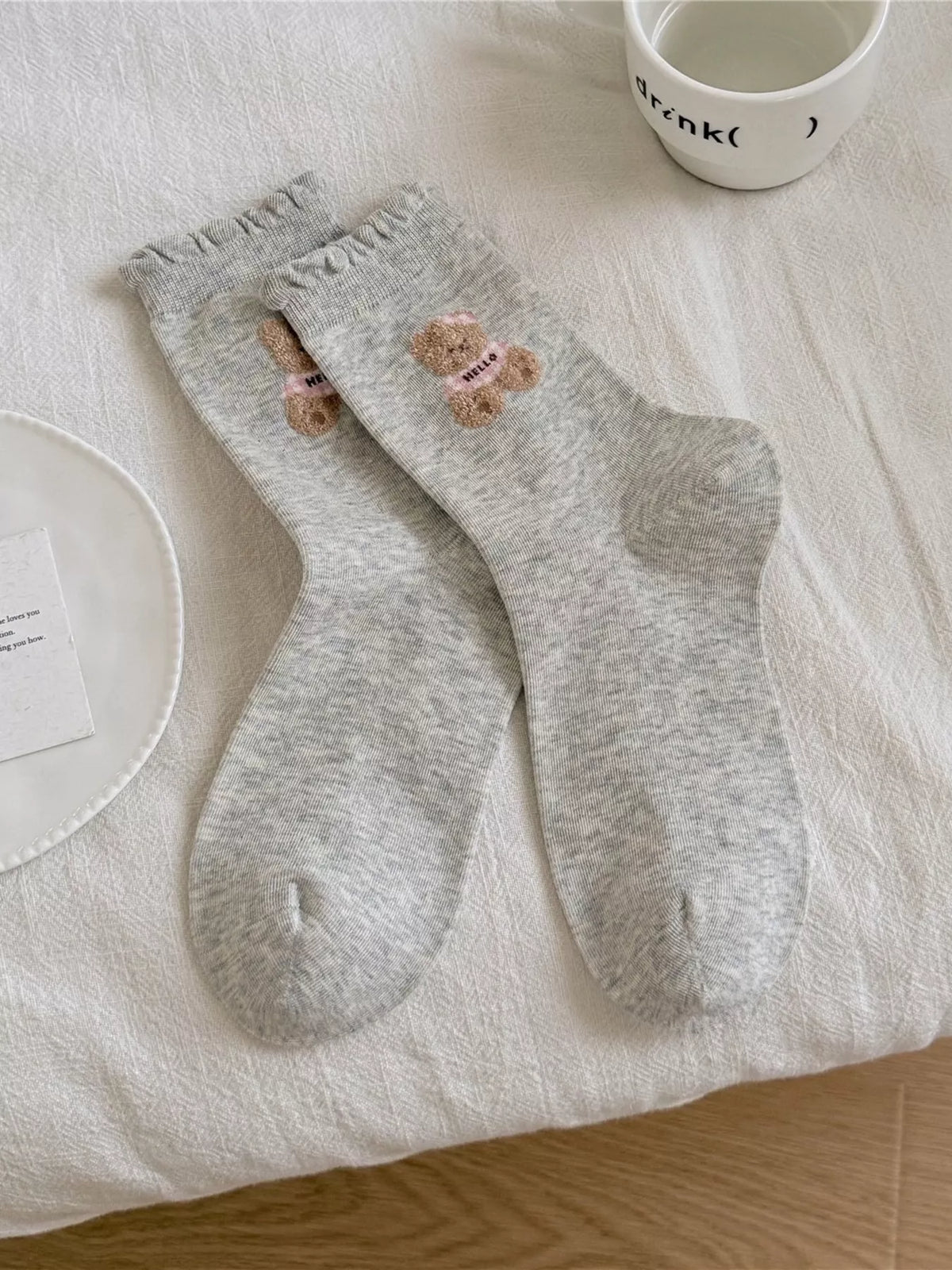 Pair of gray crew socks with bear motif laid flat