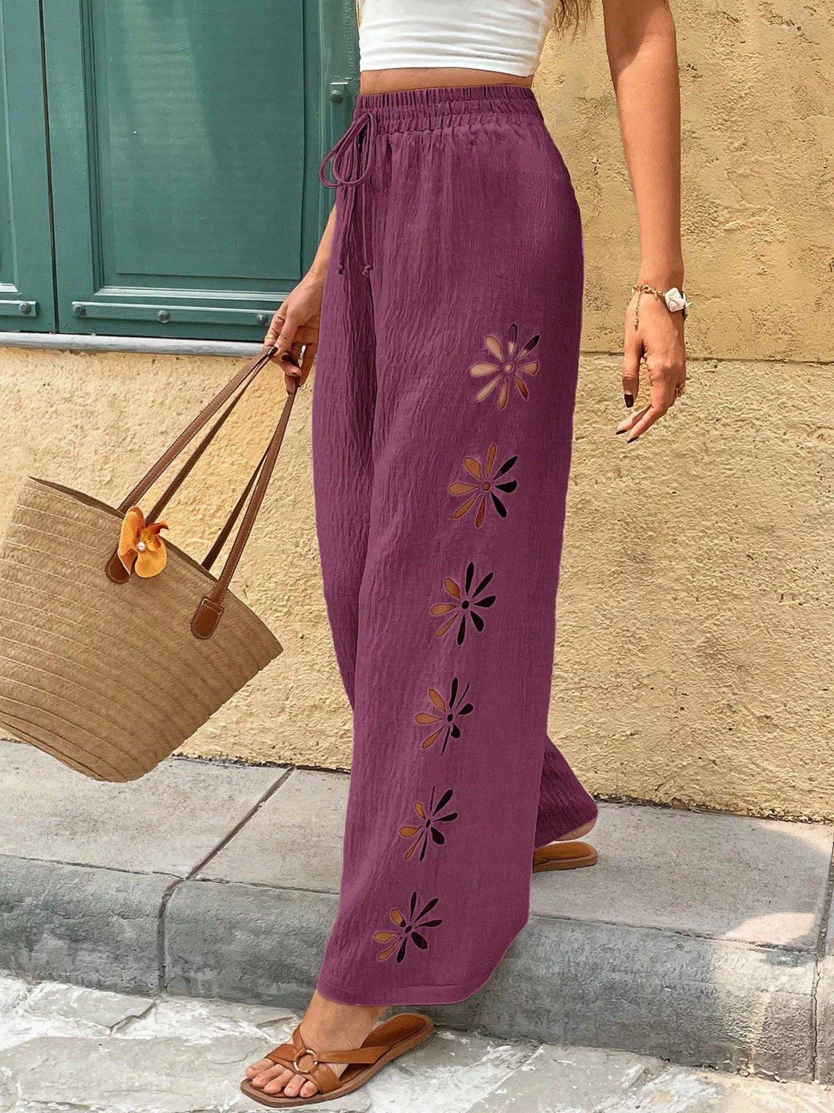 Plum pants with floral cutout embroidery along the leg
