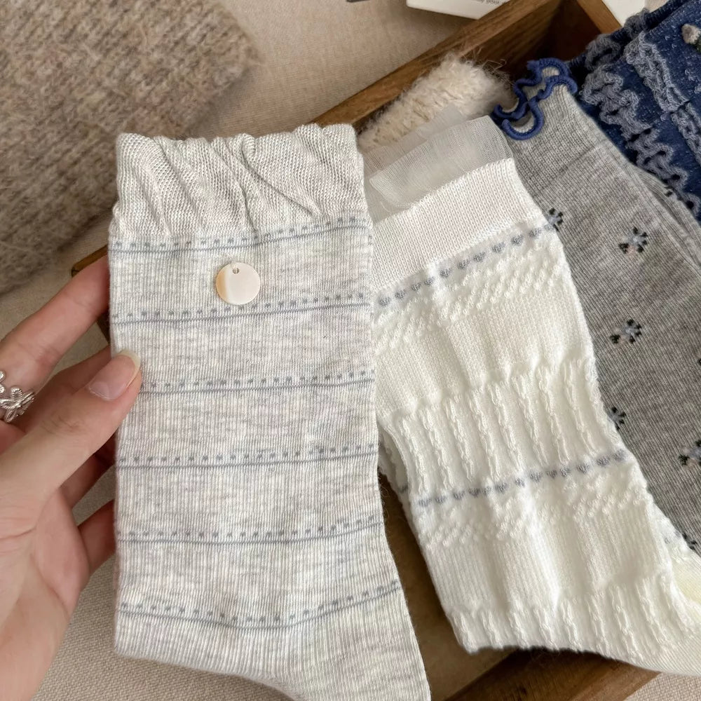 Pair of white patterned knit socks laid flat
