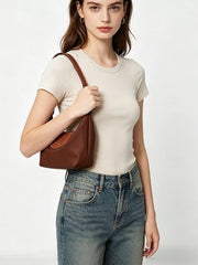 Model wearing the brown shoulder bag tucked under the arm, with the front flap visible.